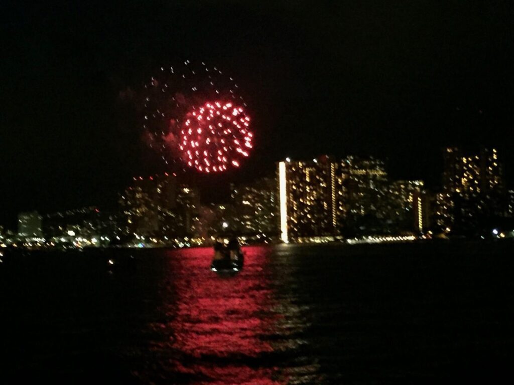Red fireworks over city skyline during sunset cruise celebration