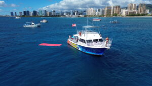 A sunset cruise boat in Waikiki with a view of the city skyline and Diamond Head in the background.