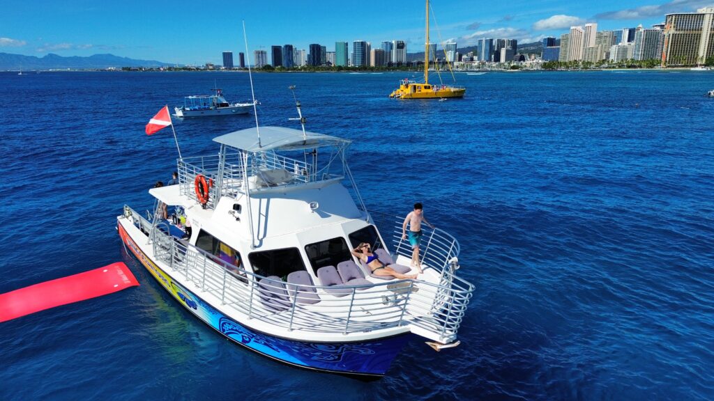 Guests relaxing on deck during a sunset cruise in Waikiki with skyline views.