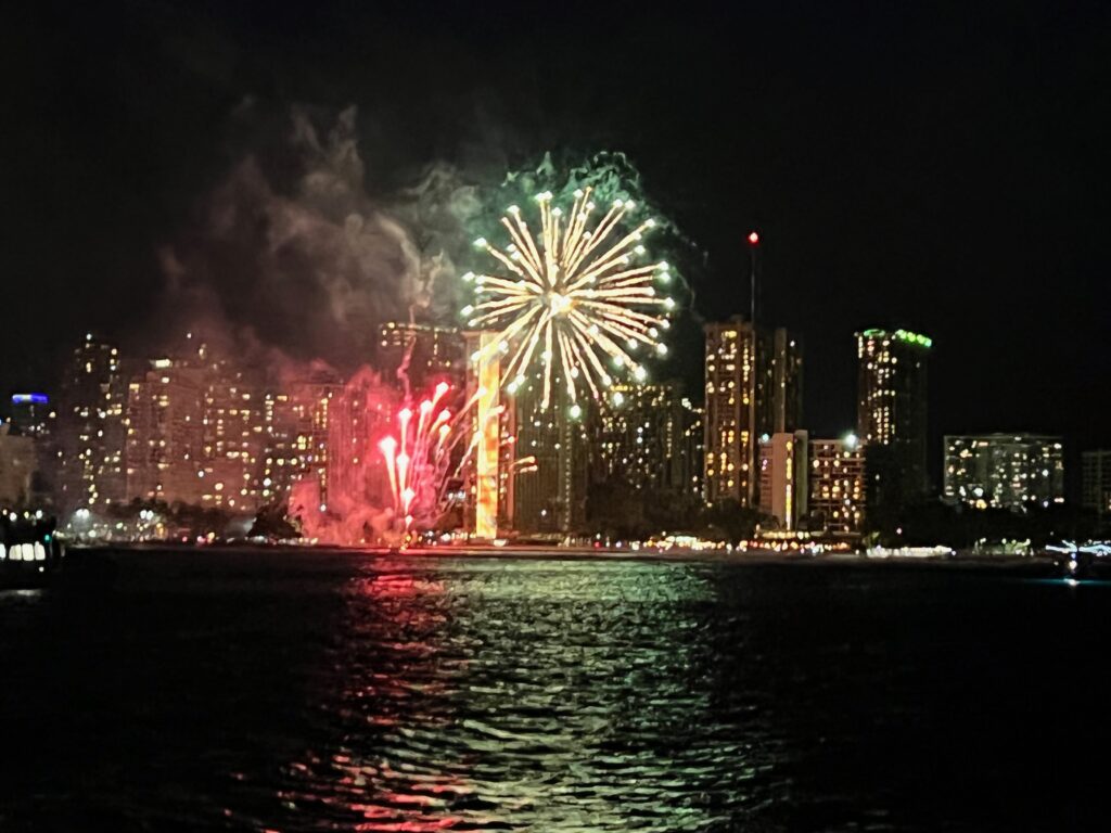 Waikiki skyline glowing at night after sunset, viewed from a boat in Oahu.